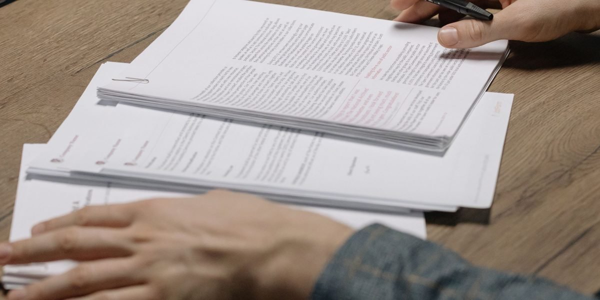 Zdjęcie osoby z uśmiechem ulgi, która właśnie znalazła poszukiwane informacje w stercie dokumentów.
